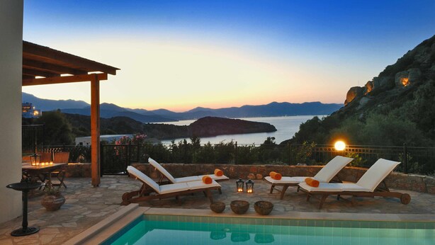 Un espace aménagé au bord de la piscine, avec des chaises longues et une pergola offrant une vue sur un paysage montagneux.