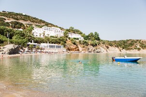 Un complejo turístico frente al mar con playa, piscina y un bote.