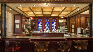 Un bar con interior de madera, una barra con taburetes y un cartel que dice "The Saints and Scholars Bar".