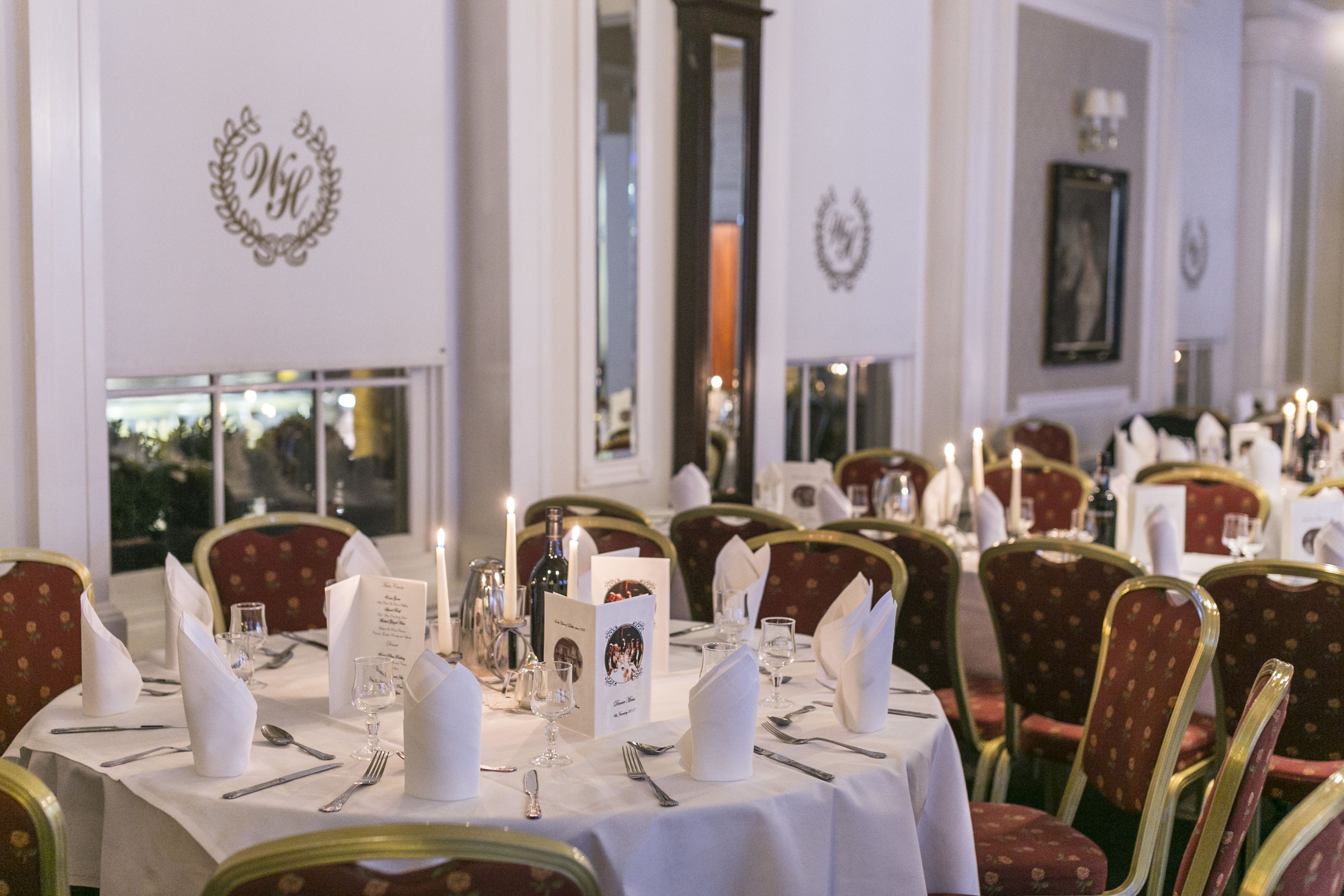 Un comedor elegante con mesas redondas, sillas tapizadas en rojo y manteles blancos.