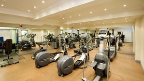 Un gimnasio con diversas máquinas de cardio, espejos y equipamiento de ejercicio.