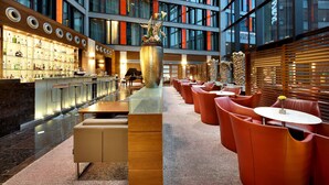 Un hall d’hôtel moderne avec un bar, des sièges et un grand vase décoratif.