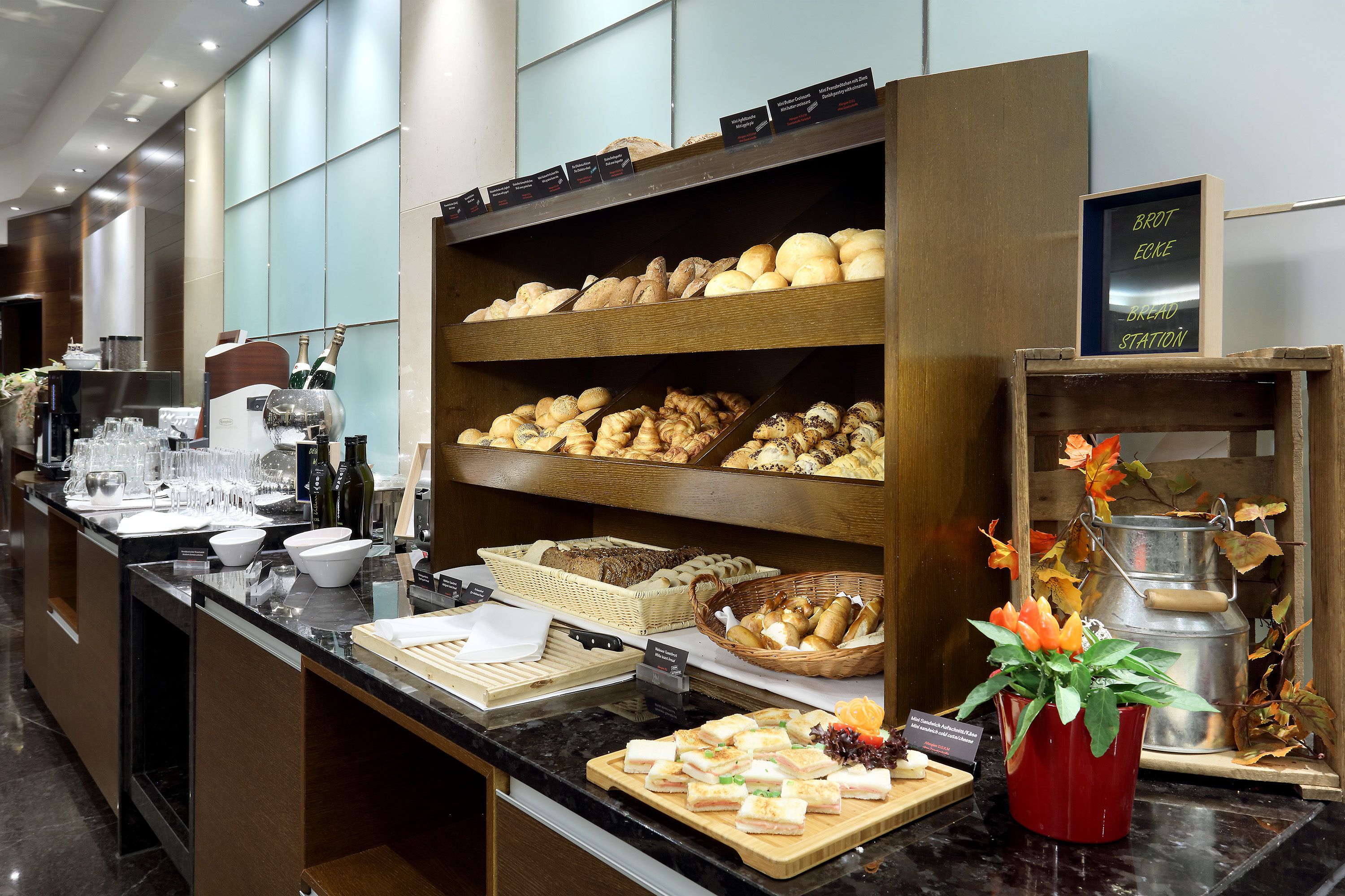 A buffet area with various food items, including breads, pastries, and sandwiches.
