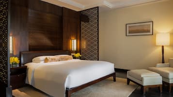 A hotel room with a large bed, a nightstand with a lamp, a chair, and a decorative wall panel.