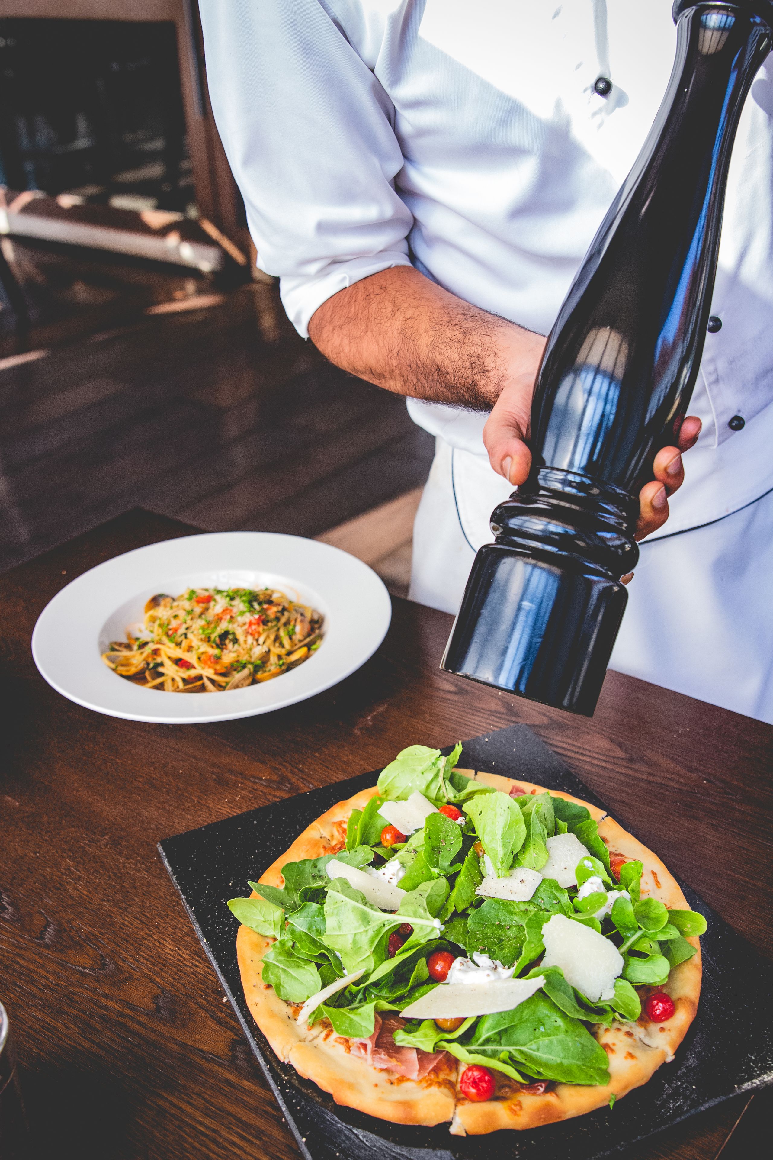A chef preparing a pizza with fresh ingredients on a wooden table.