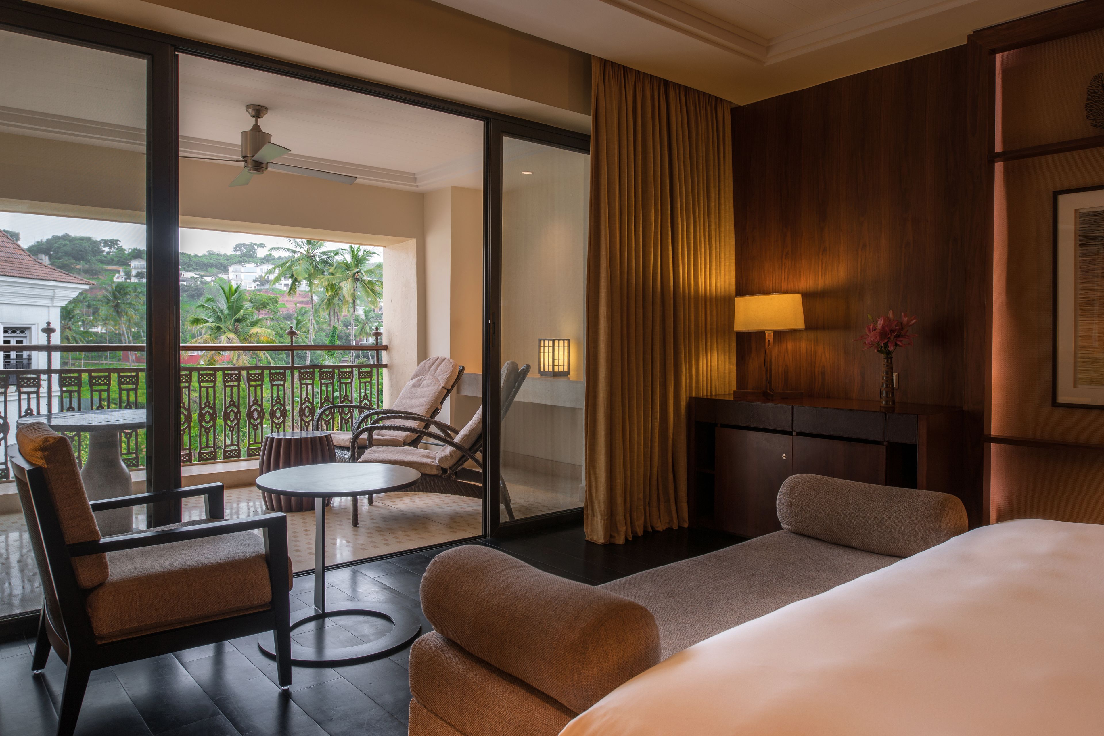 Een hotelkamer met balkon, een bank, een stoel, een tafel en een bed.
