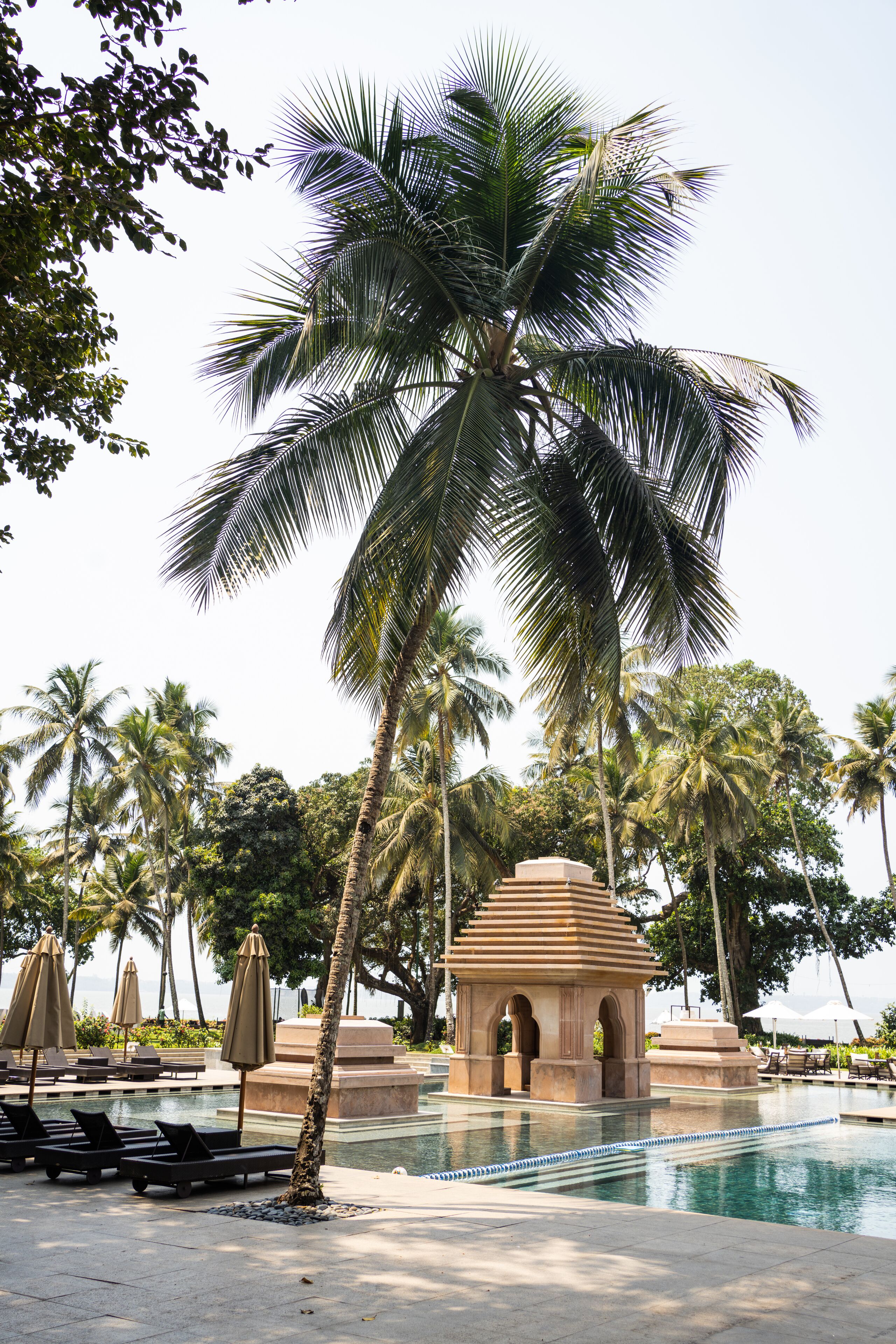 A pool area with lounge chairs, umbrellas, and a small pavilion.