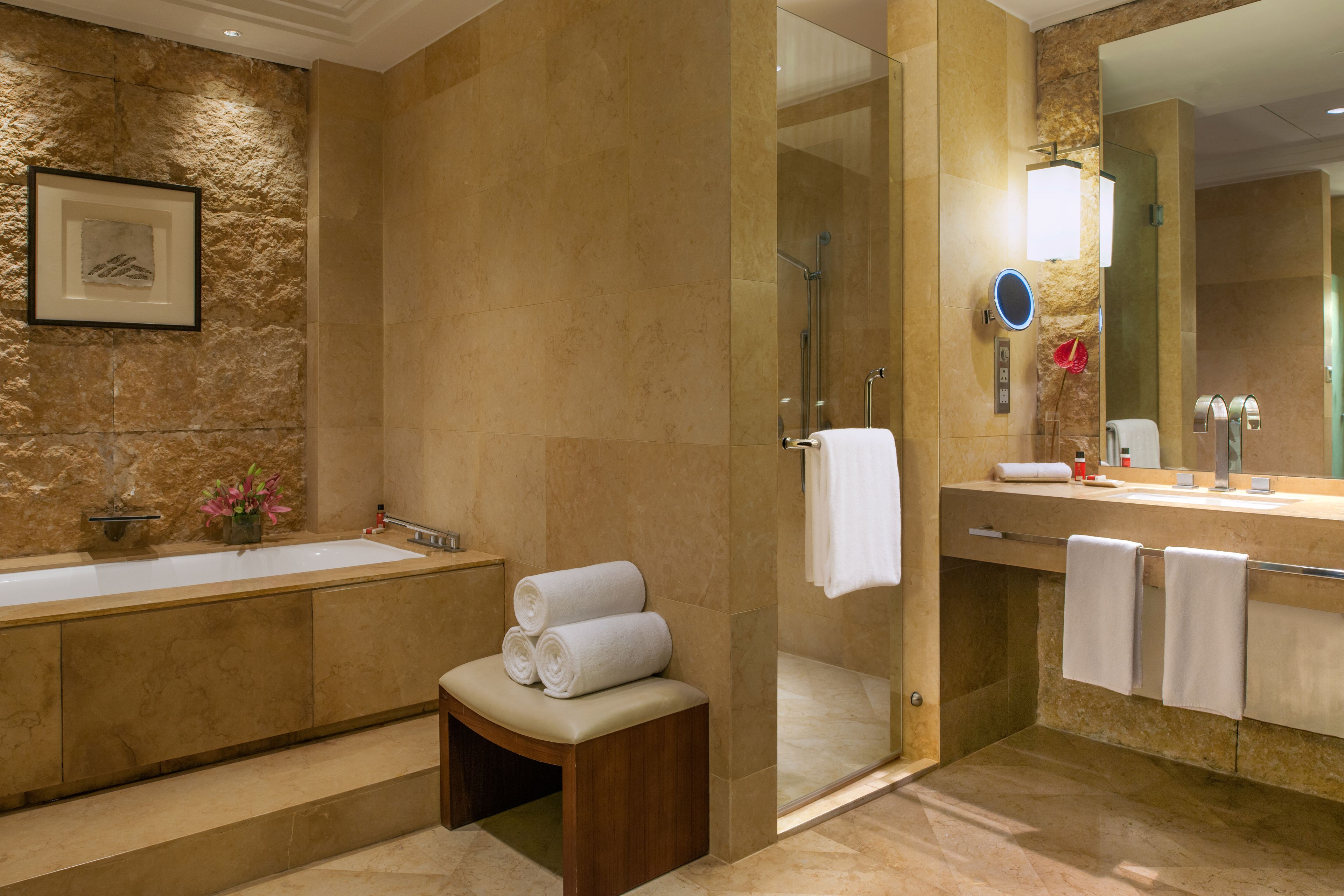 A modern bathroom with a large bathtub, a separate shower area, and a vanity with a mirror.