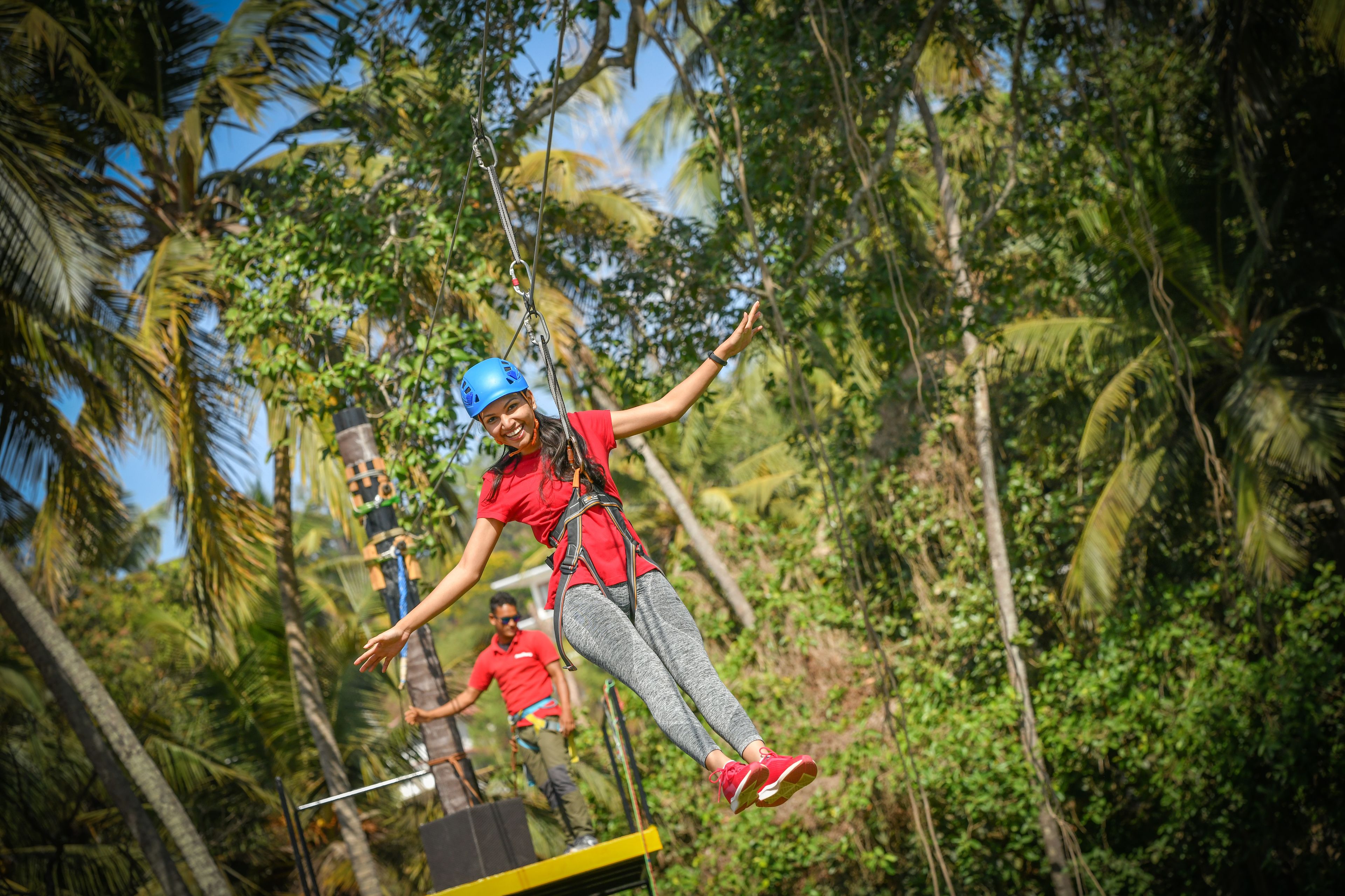 A person zip-lining through a lush, tropical forest.