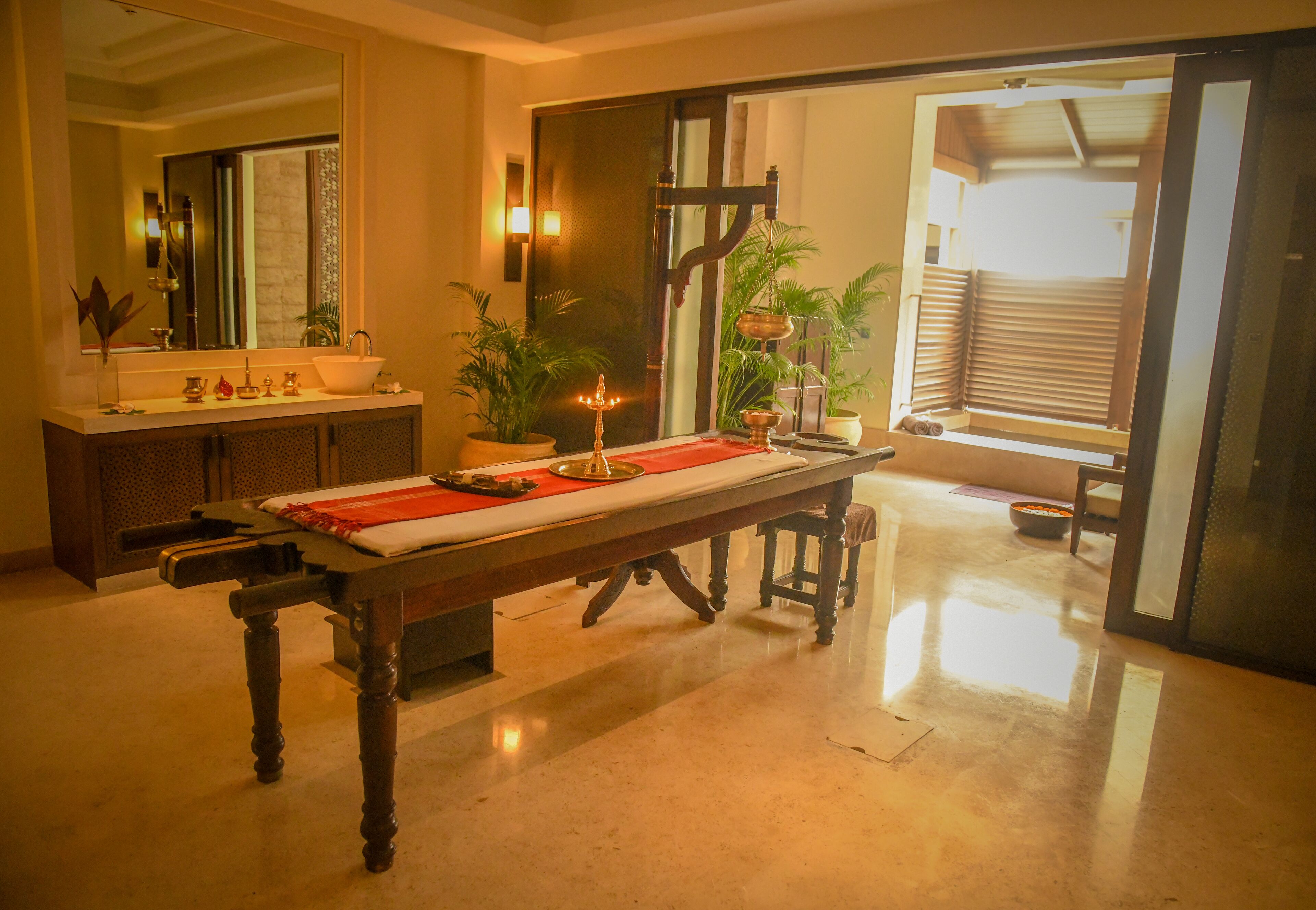 A room with a dining table set for a meal, a sink with toiletries, and a mirror.