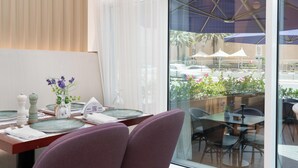 Zona pranzo con tavolo imbandito per due persone, un vaso con fiori e vista sulla zona salotto esterna.