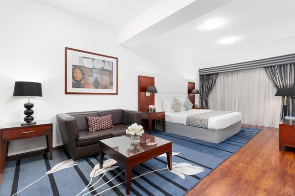 Una habitación de hotel moderna con cama, sofá, mesa de centro y escritorio.