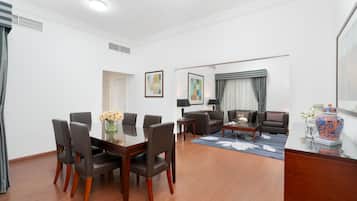 A modern living room with a dining area, featuring a wooden dining table, chairs, a sofa, and a coffee table.