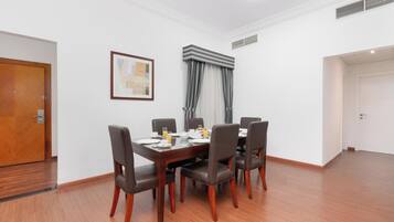 Un comedor con mesa y sillas de madera, un cuadro en la pared y una ventana con cortinas.