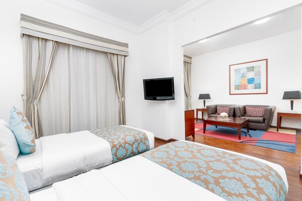 Une chambre d’hôtel avec deux lits, un téléviseur à écran plat, un canapé et une table basse.