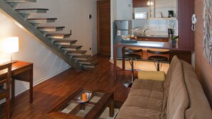 A modern living room with a staircase, a dining area, and a kitchen. - Park Plaza Apart Hotel (Santiago)