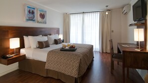 A hotel room with a large bed, bedside tables, a desk, and a TV. - Park Plaza Apart Hotel (Santiago)