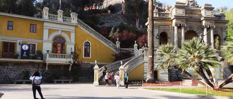 Un edificio histórico con fachada amarilla, una gran escalera y arquitectura clásica.