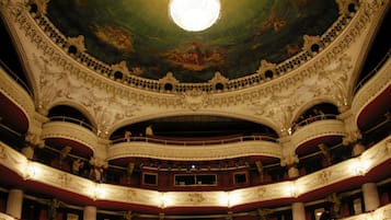 Un teatro majestuoso con arquitectura ornamentada, varios balcones y un candelabro central.