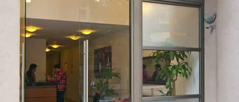 A hotel entrance with a reception desk, a glass door with the number 545, and a doormat with a 'PARK' symbol.