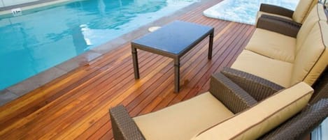 Una piscina al aire libre, sillones reclinables de piscina