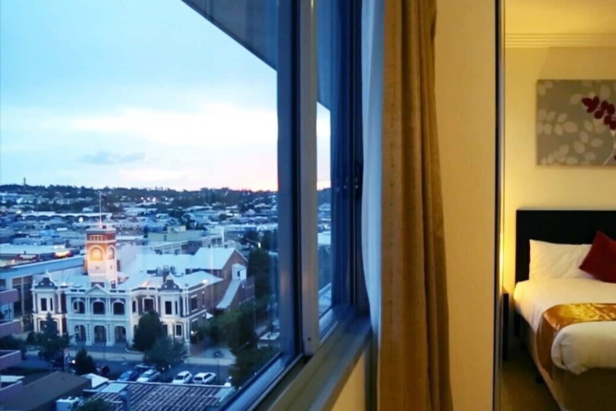 Ein Hotelzimmer mit einem Bett, einem Nachttisch, einer Lampe und einem Bild an der Wand.