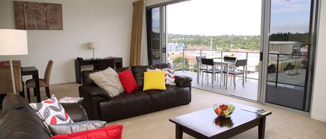 A modern living room with a leather sofa, a coffee table, and a dining area with a table and chairs.