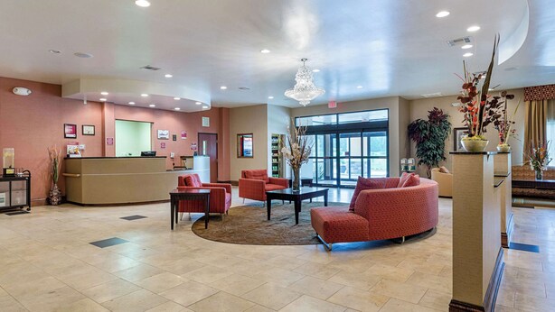 A hotel lobby with a reception desk, seating area, and large windows.