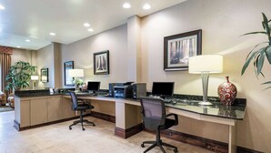 A hotel reception area with a counter, computers, office chairs, and framed pictures on the wall.