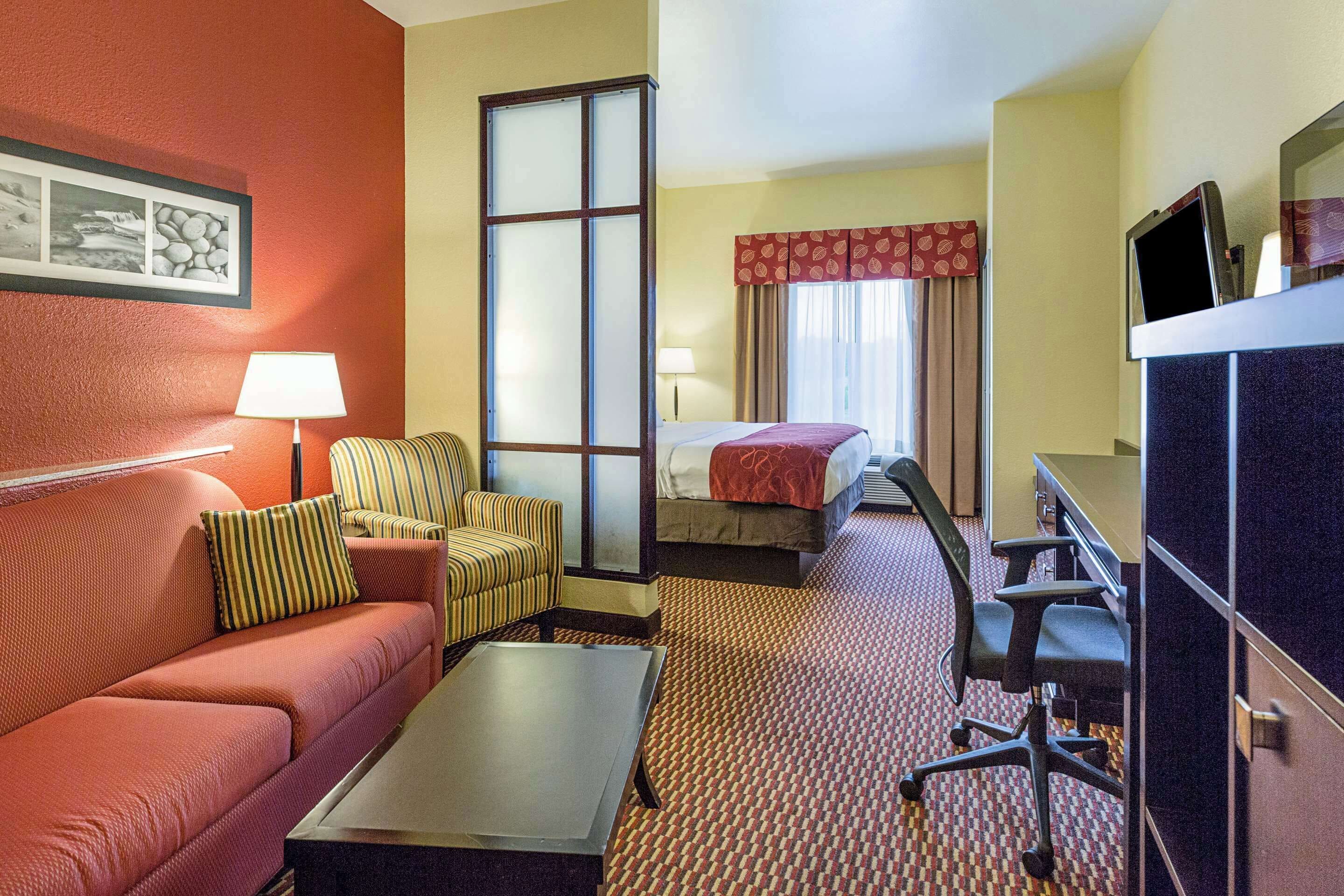 A hotel room with a sofa, armchair, desk, and a bed.