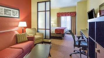 A hotel room with a sofa, armchair, desk, and a bed.