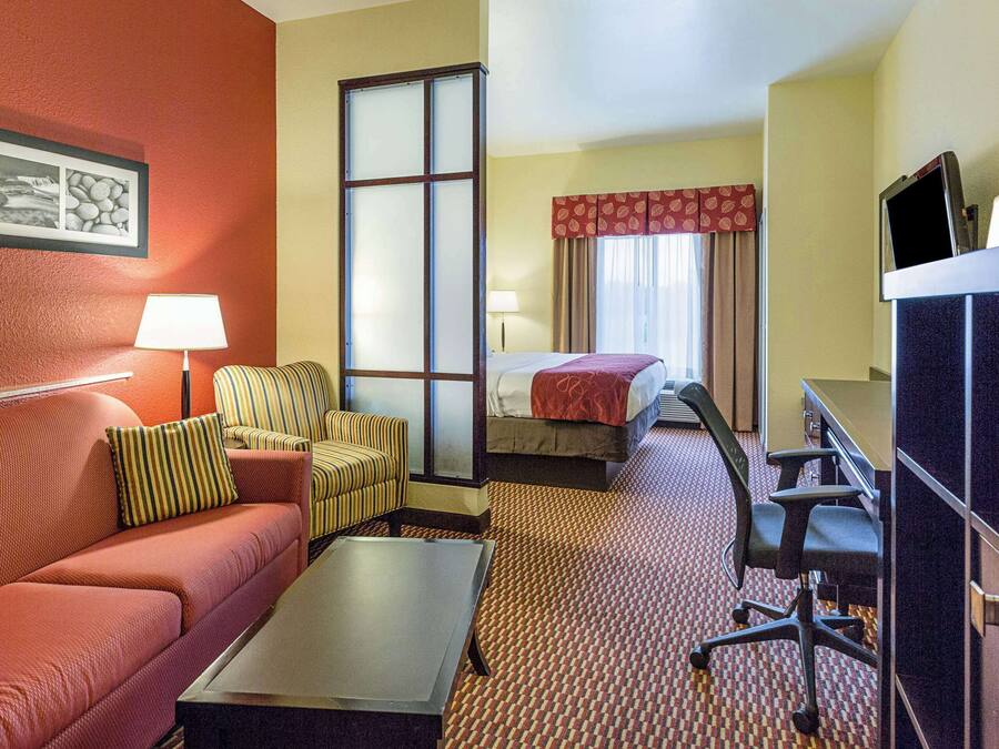 A hotel room with a sofa, armchair, desk, and a bed.