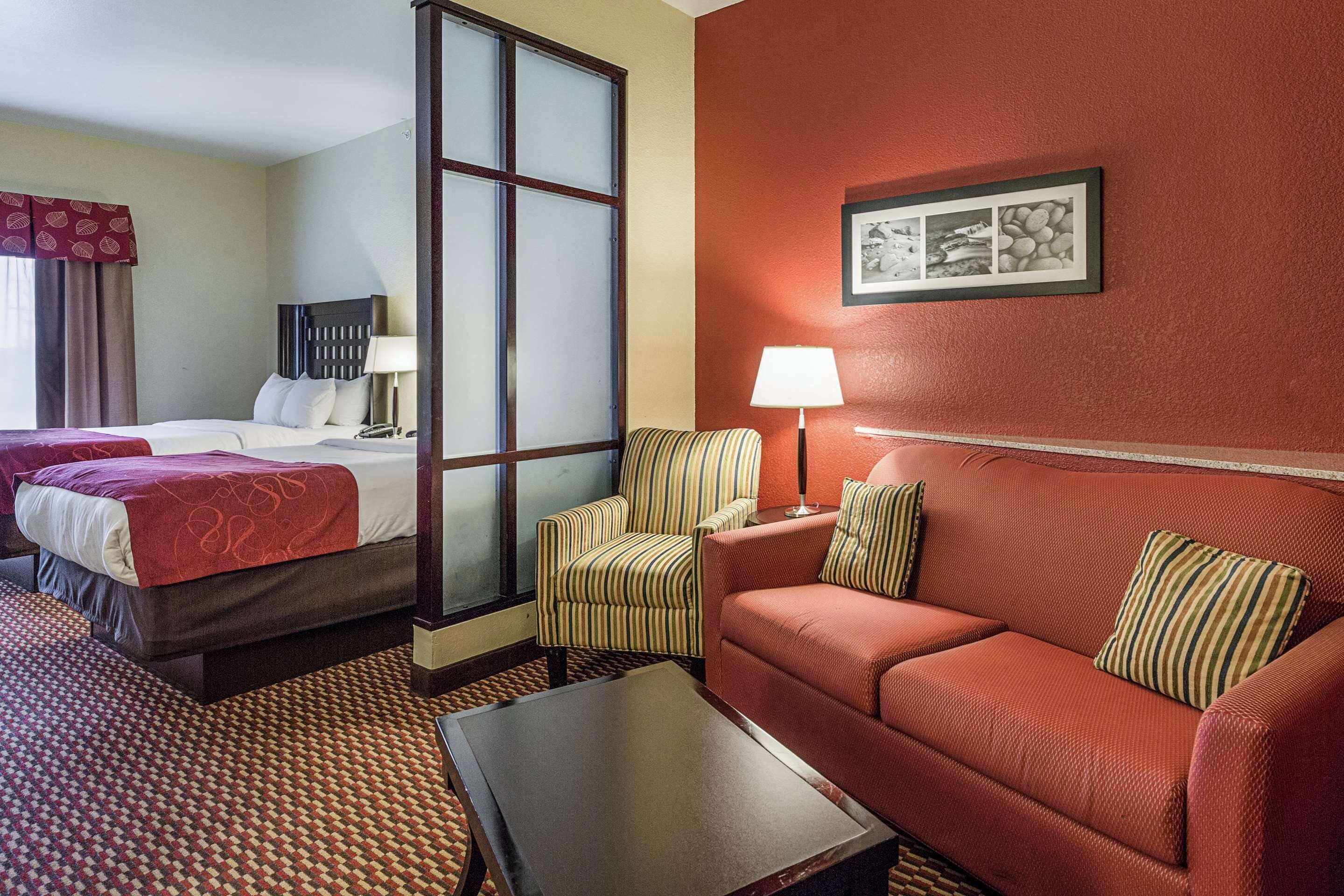 A hotel room with a bed, a sofa, a chair, a coffee table, and a wall-mounted picture.