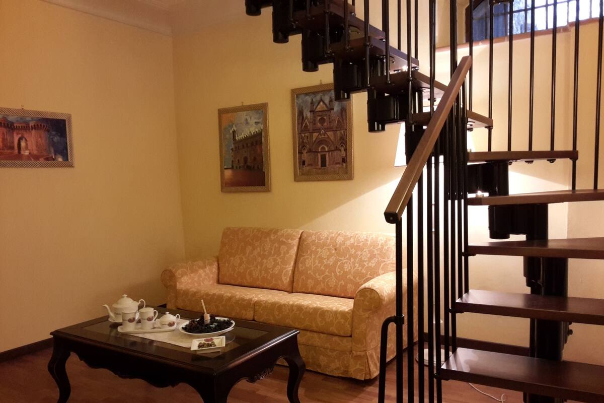 A living room with a sofa, a coffee table, and a staircase.