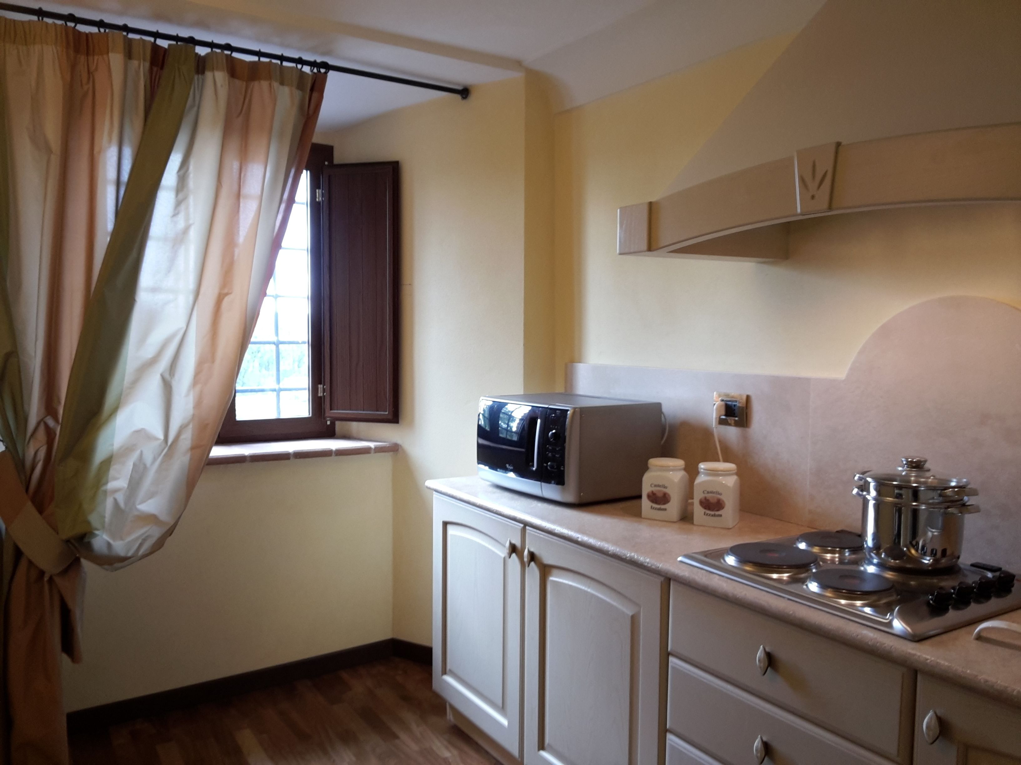Una cocina compacta con microondas, estufa y dos frascos de condimentos.
