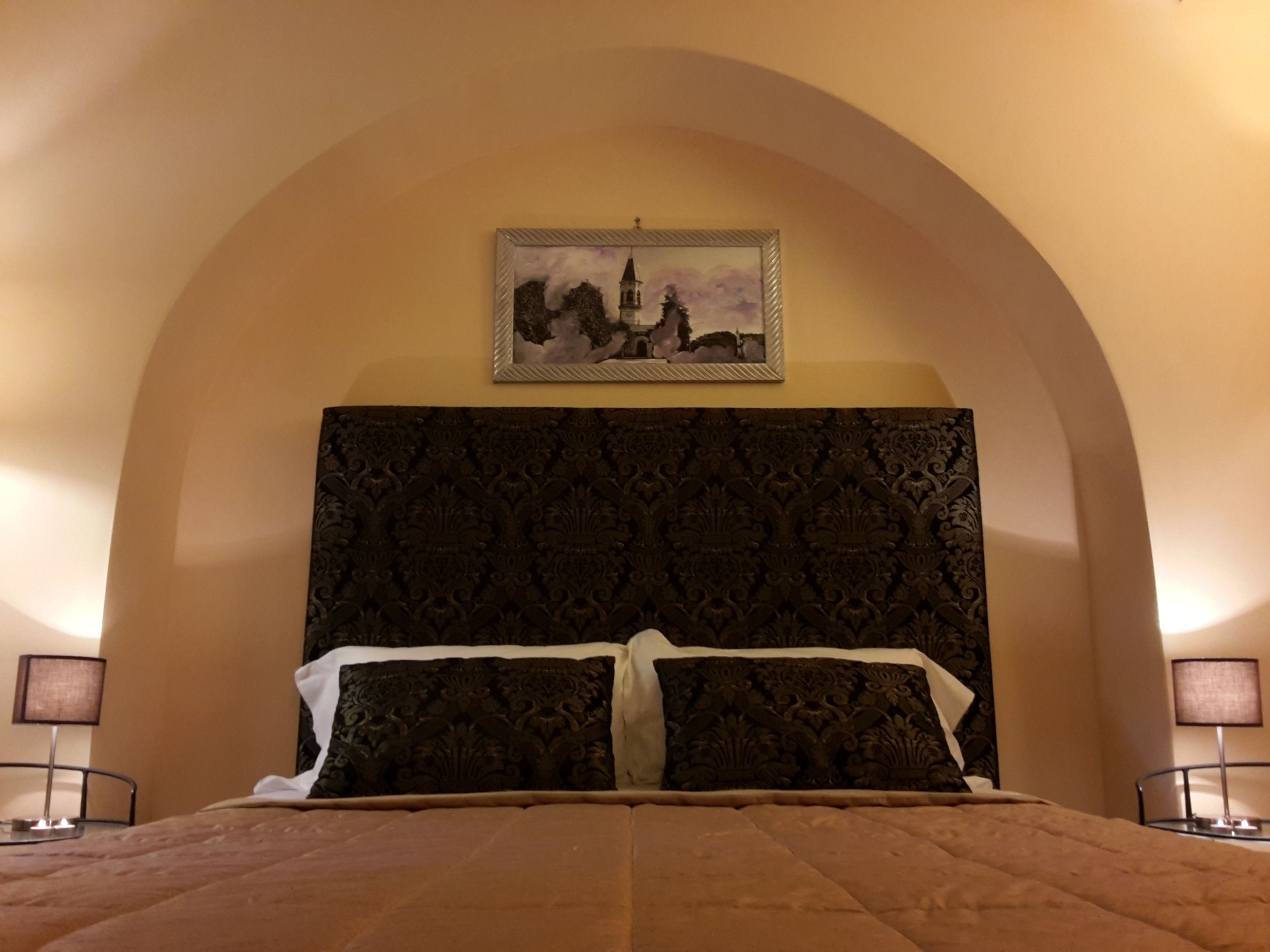 Une chambre à coucher avec un grand lit, une tête de lit décorée et un tableau encadré au-dessus.