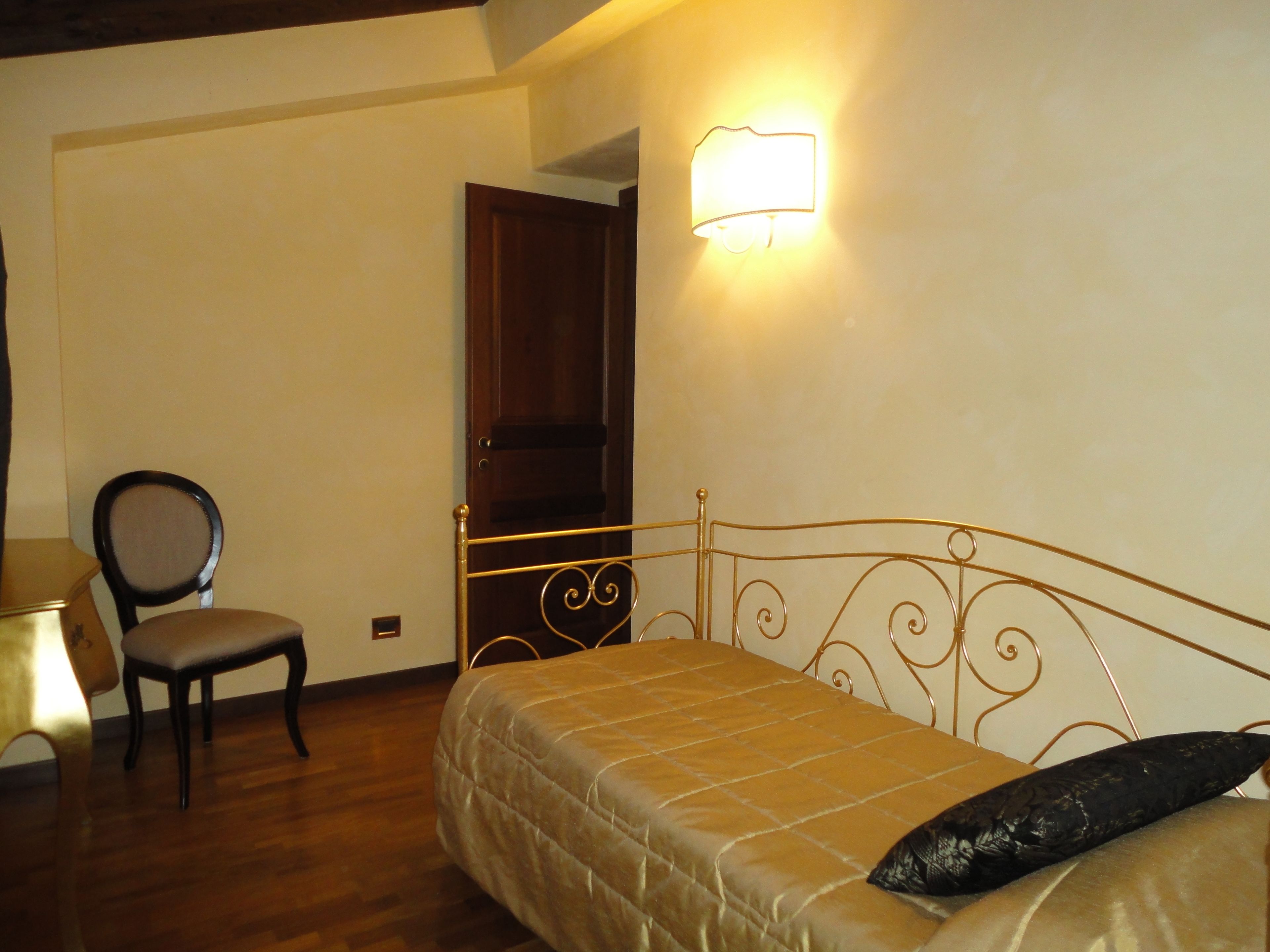 A bedroom with a bed, a chair, and a wall-mounted light fixture.