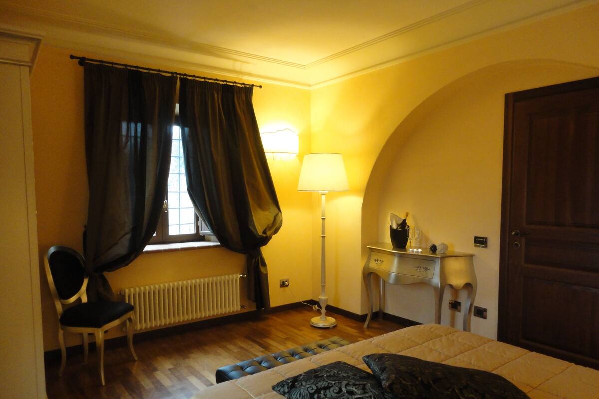 A hotel room with a bed, a chair, a desk, a lamp, and a door.