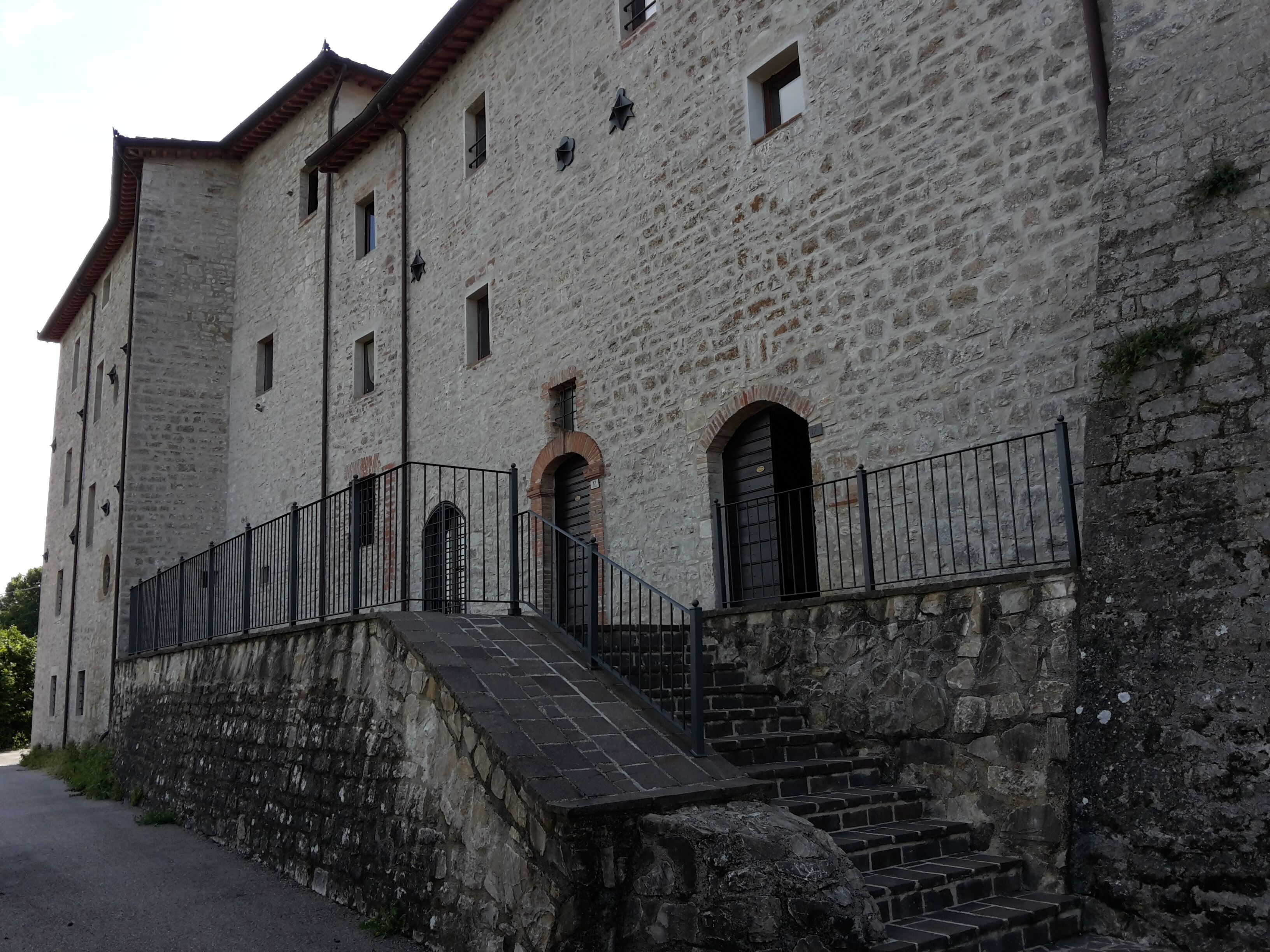 A stone building with multiple windows and a staircase leading to an entrance.