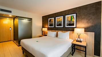 Hotelkamer met een groot bed, twee nachtkastjes, een tv aan de muur en een deur naar de badkamer.