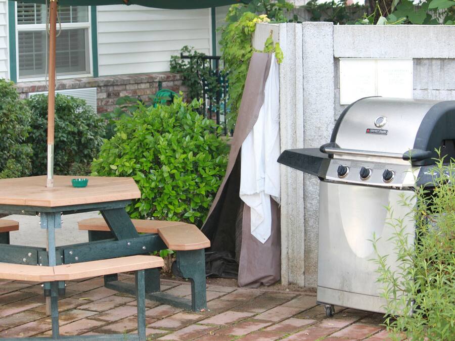 A patio with a picnic table and a barbecue grill.