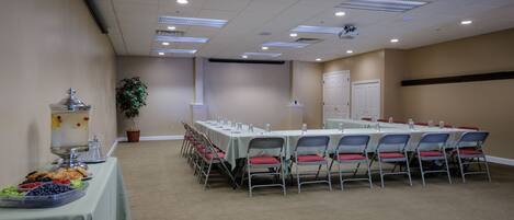 A conference room with a long table, chairs, and a buffet table with food.