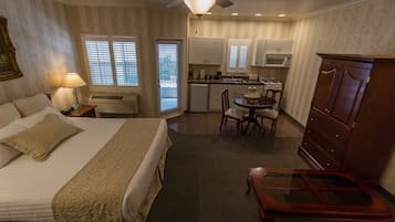 Habitación de hotel con cama, escritorio, silla, cómoda, ventilador de techo y kitchenette.