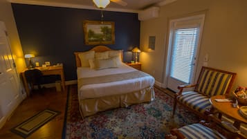 Ein Schlafzimmer mit Bett, Schreibtisch, Stuhl, Tisch und Deckenventilator.