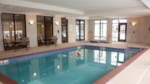 An indoor swimming pool with clear water, a lifeguard chair, and a poolside area with chairs and tables. - Hampton Inn Burlington (Burlington)