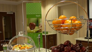 A buffet setup with a fruit bowl and a fruit basket on a granite countertop. - Hampton Inn Burlington (Burlington)