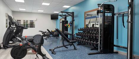 A gym with cardio equipment, weight machines, and dumbbells.