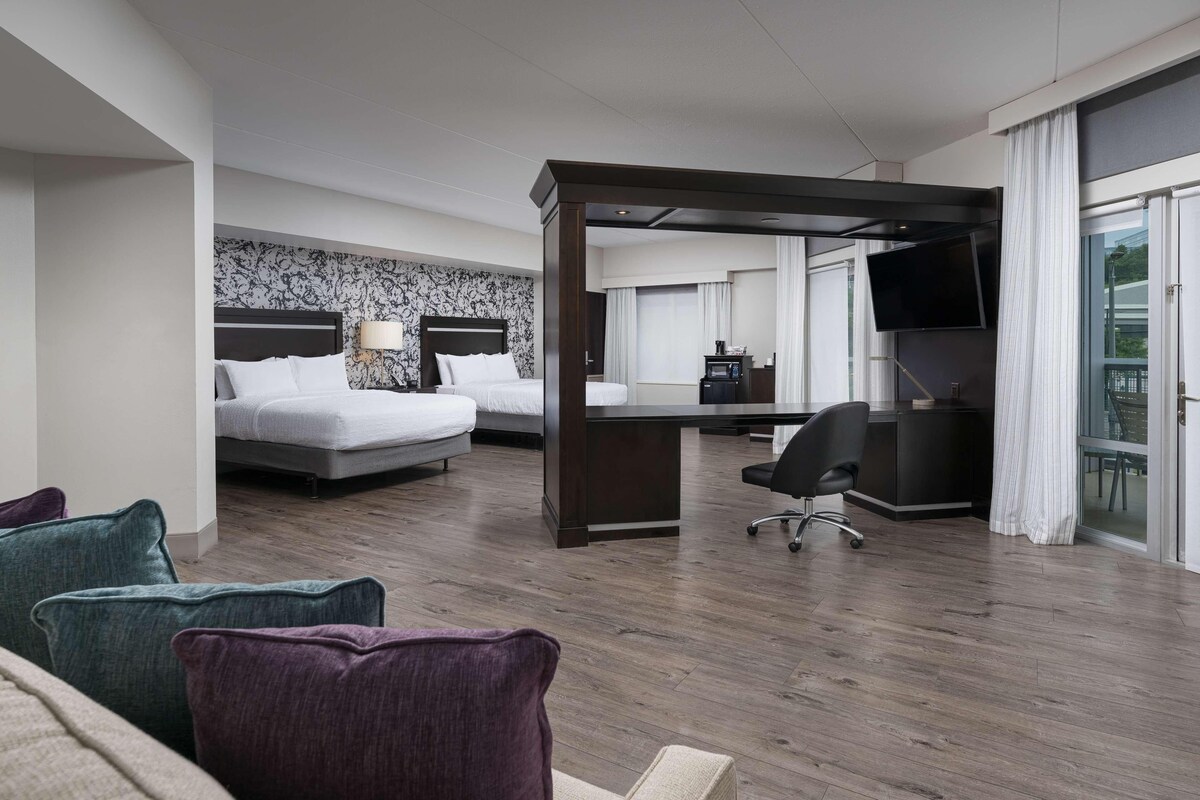 A hotel room with a bed, a desk, a chair, and a television.