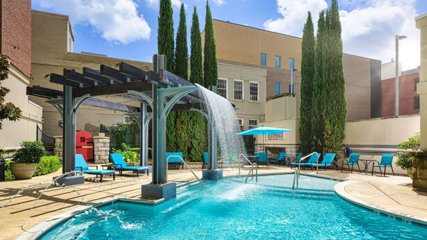 A swimming pool with a waterfall feature, surrounded by lounge chairs and a pergola. - Hampton Inn & Suites Chattanooga/Downtown (Chattanooga)