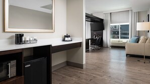 A modern hotel room with a kitchenette, a large mirror, a sofa, and a TV. - Hampton Inn & Suites Chattanooga/Downtown (Chattanooga)